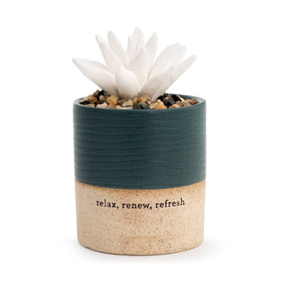 DEMDACO Succulent Oil Diffuser Relax — hand-sculpted white ceramic succulent nestled in decorative pebbles inside a two-tone ceramic pot with rich teal top and warm sandy natural clay base stamped with "relax, renew, refresh"