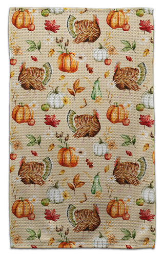 A eco-friendly woven kitchen towel with a repeating autumn harvest pattern featuring pumpkins, turkeys, acorns, leaves, and small gourds on a beige background.