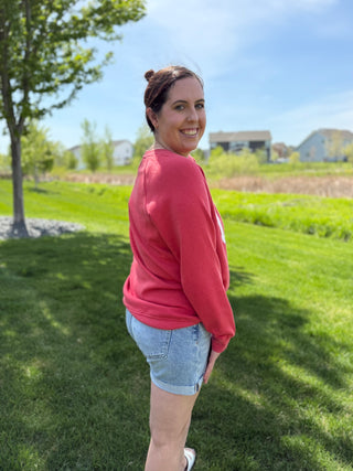 Woman wearing red USA patriotic graphic sweatshirt with distressed white lettering