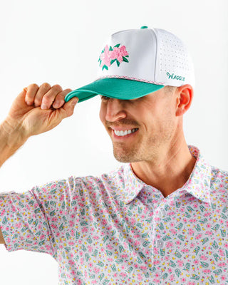 Man wearing a white cap with floral design and colorful shirt on a white background