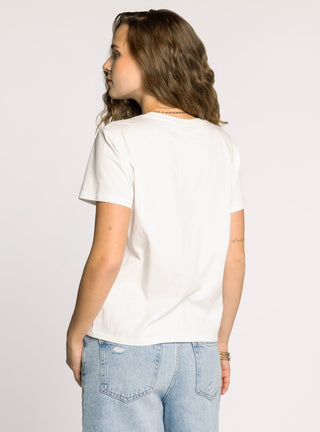 Woman wearing a white t-shirt and light blue jeans on a plain background